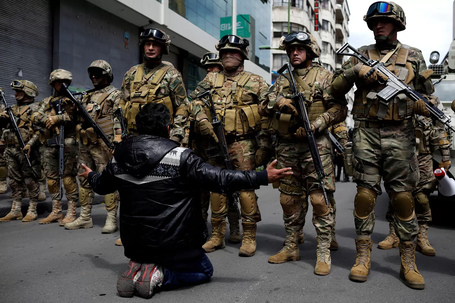 BASTA. Un ciudadano se arrodilla frente a un cordón humano del ejercito boliviano en La Paz. REUTERS