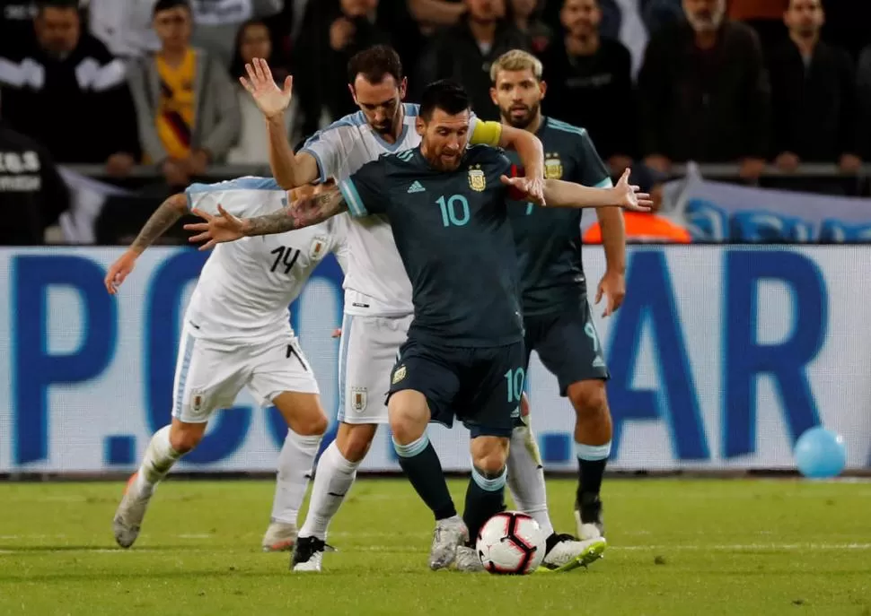 CON LA PELOTA DOMINADA. Lionel Messi maniobra ante la marca de Diego Godín, mientras Lucas Torreira (14) y el “Kun” Agüero sigue de cerca la jugada. reuters