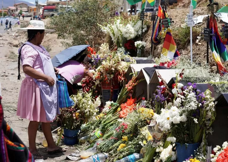 LUTO. Dos mujeres dejan ofrendas florales en pequeños monumentos. reuters