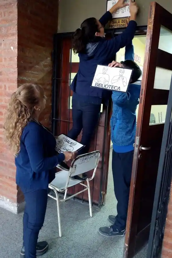 EN PRÁCTICA. Los docentes colocan uno de los carteles identificatorios.