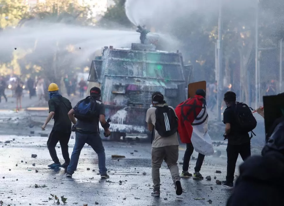 SIN TREGUA. Los manifestantes chilenos enfrentaron a las tanquetas hidrantes con piedras y gomeras.  reuters 