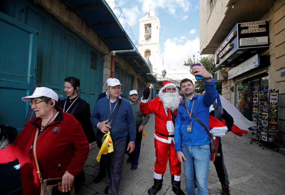  ESPÍRITU NAVIDEÑO. Un turista se saca una foto junto a un palestino vestido como Papá Noel, en una calle de Belén.