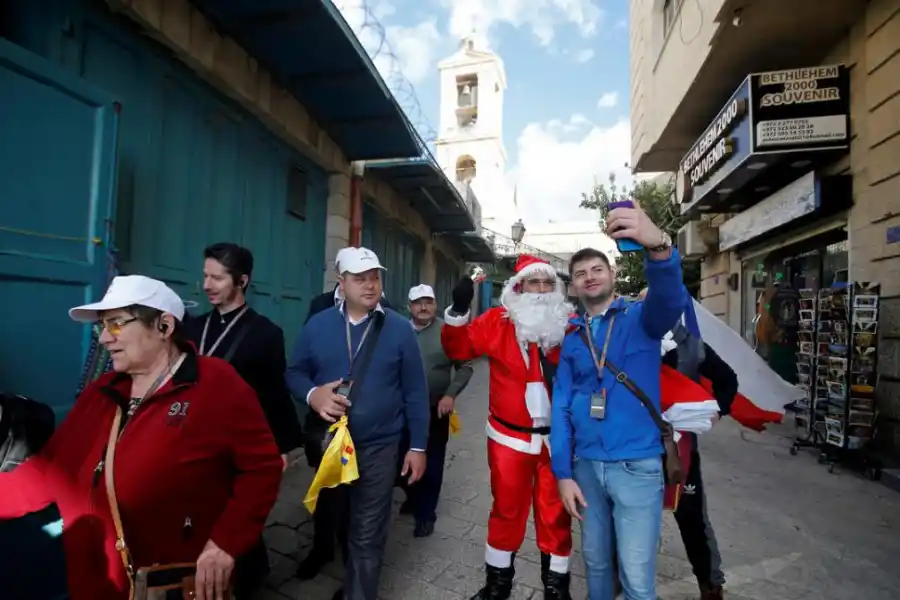  ESPÍRITU NAVIDEÑO. Un turista se saca una foto junto a un palestino vestido como Papá Noel, en una calle de Belén.