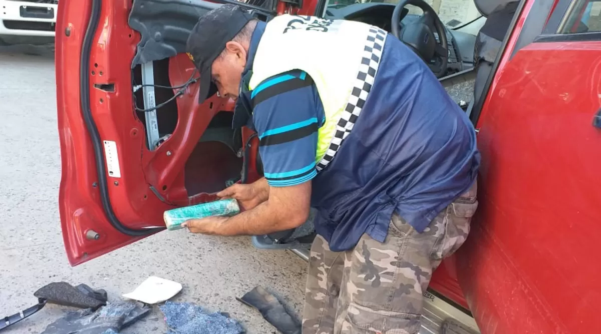 EN PLENA REQUISA. Un efectivo extrae la droga de un panel de una de las puertas de la camioneta.  