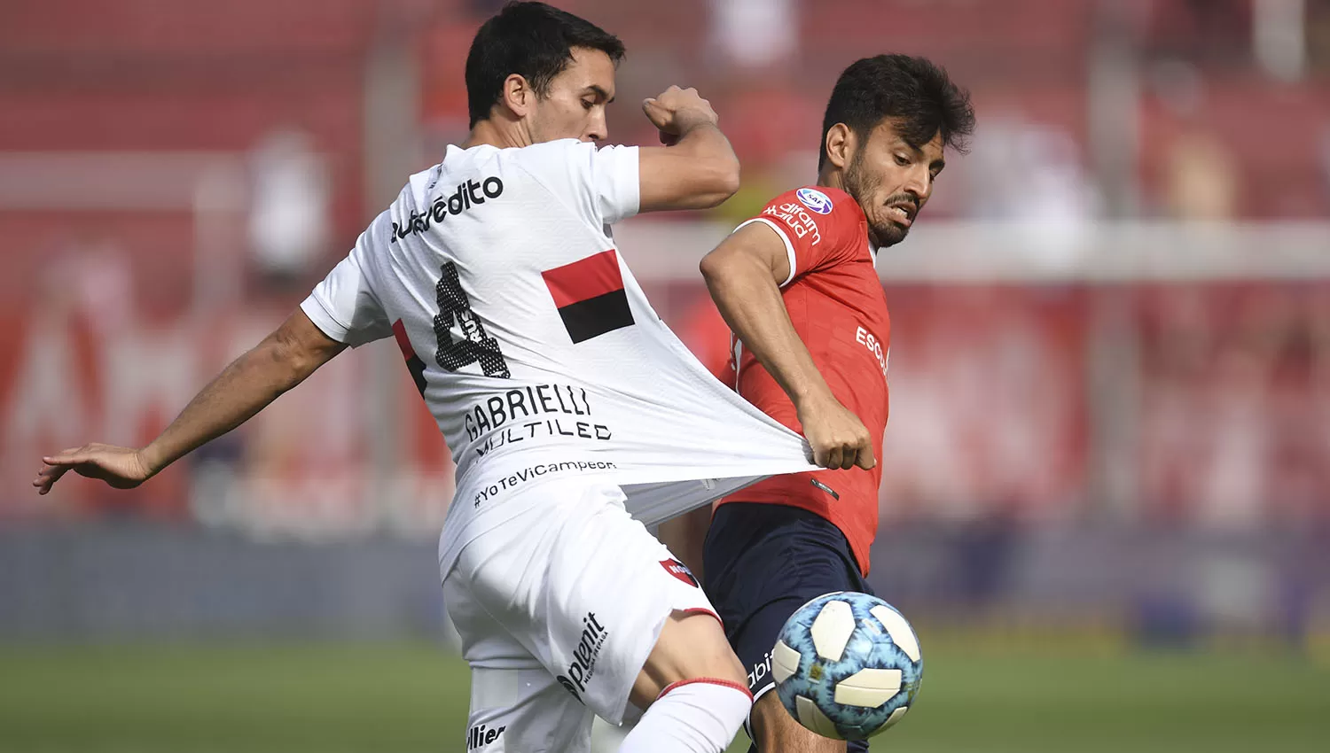 Gabrielli, de Newell's, y Sánchez Miño, del Rojo, disputan la posesión de la pelota. (TÉLAM)