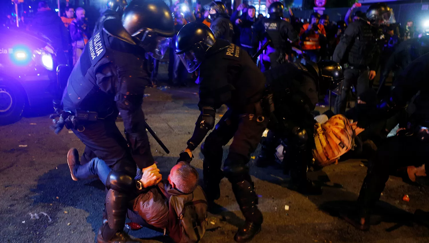 Dos efectivos policiales reducen a uno de los manifestantes. (Reuters)
