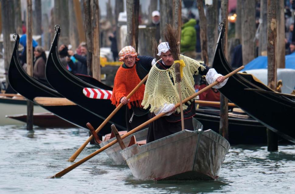 VENECIA. Dos hombres disfrazados de Bufana, la bruja buena que les da regalos a los niños el 6 de enero, navegan por el Gran Canal.