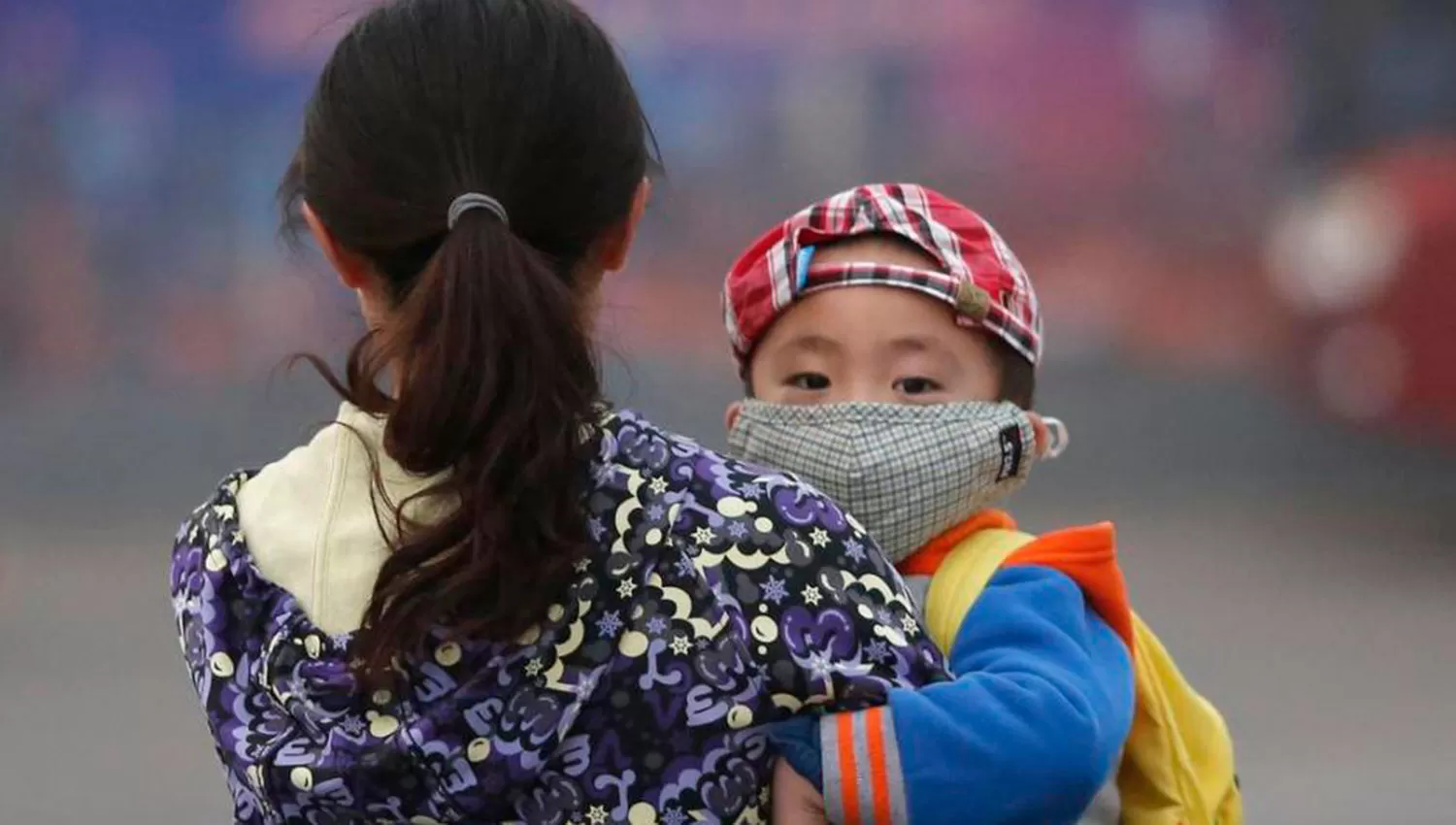 CUIDADOS. Un niño chino con barbijo en brazos de su madre ARCHIVO.