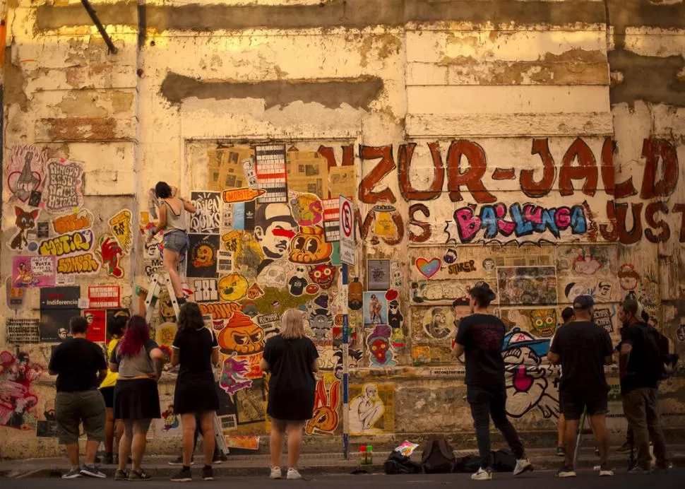 EN PROCESO. una pegatina colectiva en proceso tapa una pintada de propaganda política en calle Virgen de la Merced credito