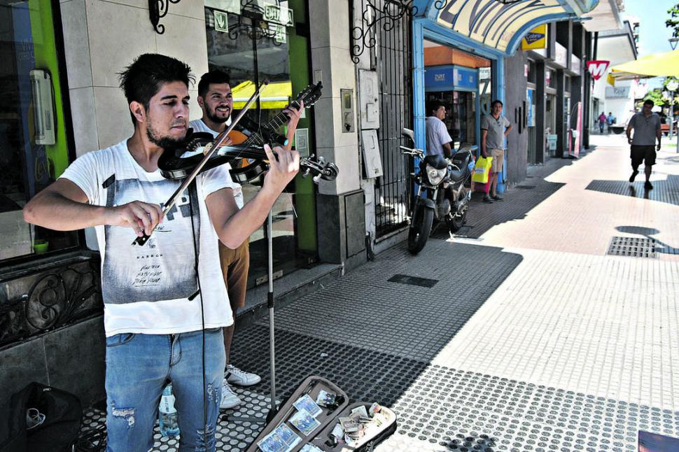 EN FAMILIA. Los hermanos Juárez, Santiago en el violín y Diego la guitarra se instalan frente al mercado del Norte.