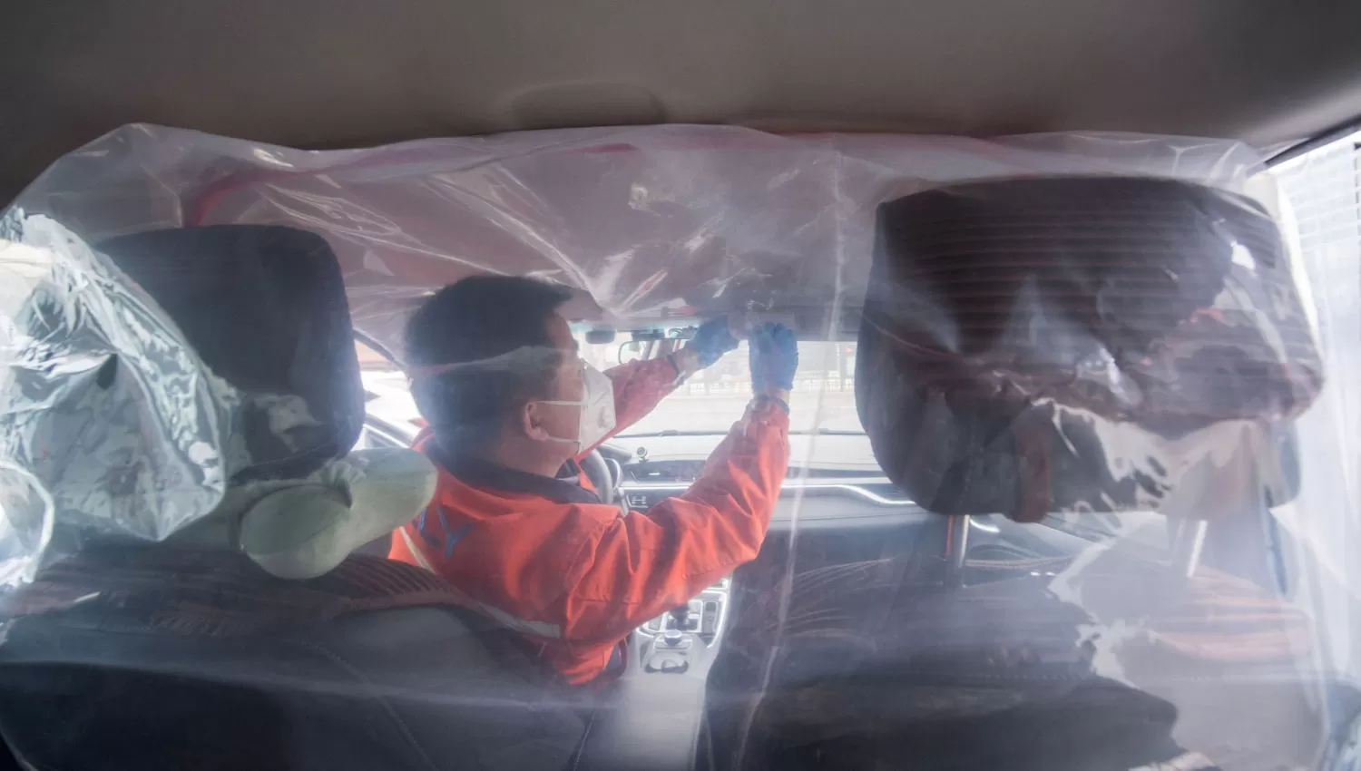 PREVENCIÓN. Un hombre coloca plásticos dentro de un taxi para separar los habitáculos entre conductor y pasajeros debido al coronavirus.