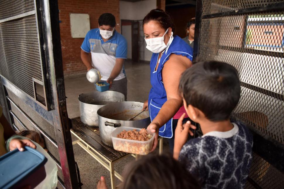 EN LA COSTANERA. Con barbijo adultos sirven la comida a los niños. la gaceta / foto de Inés Quinteros Orio