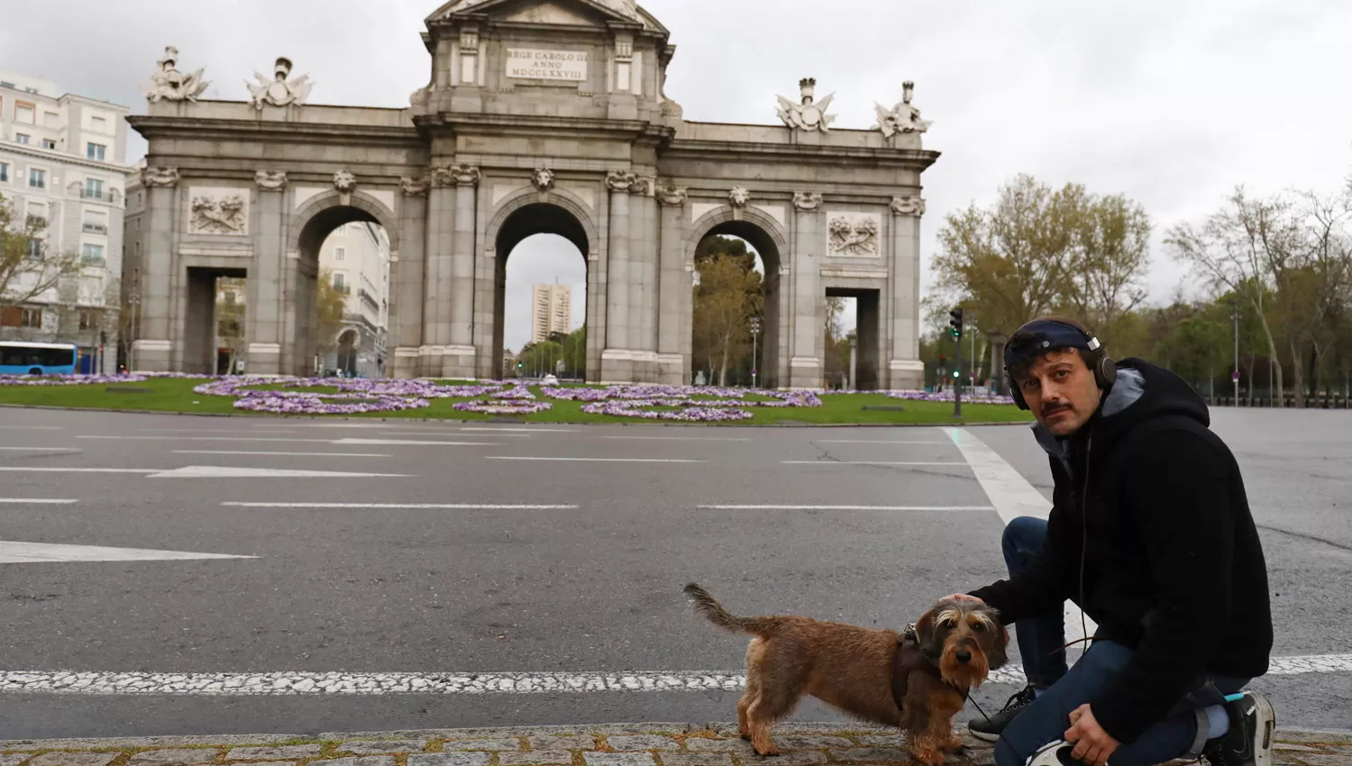 CALLES VACÍAS. Un joven posó junto a su mascota frente a una Puerta de Alcalá desierta, en el centro de Madrid.
