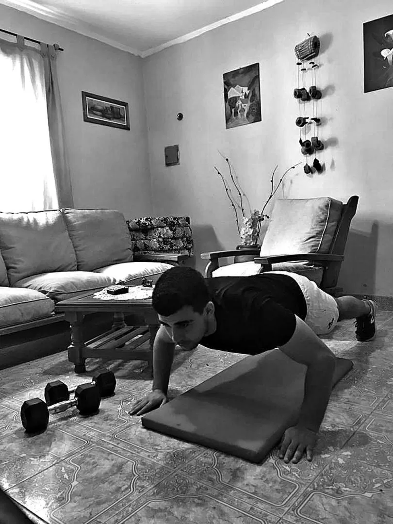 EN EL LIVING DE CASA. Nicolás Fonollat trabaja sobre una colchoneta y realiza flexiones de brazos. A pesar de la cuarentena, sigue entrenándose. 