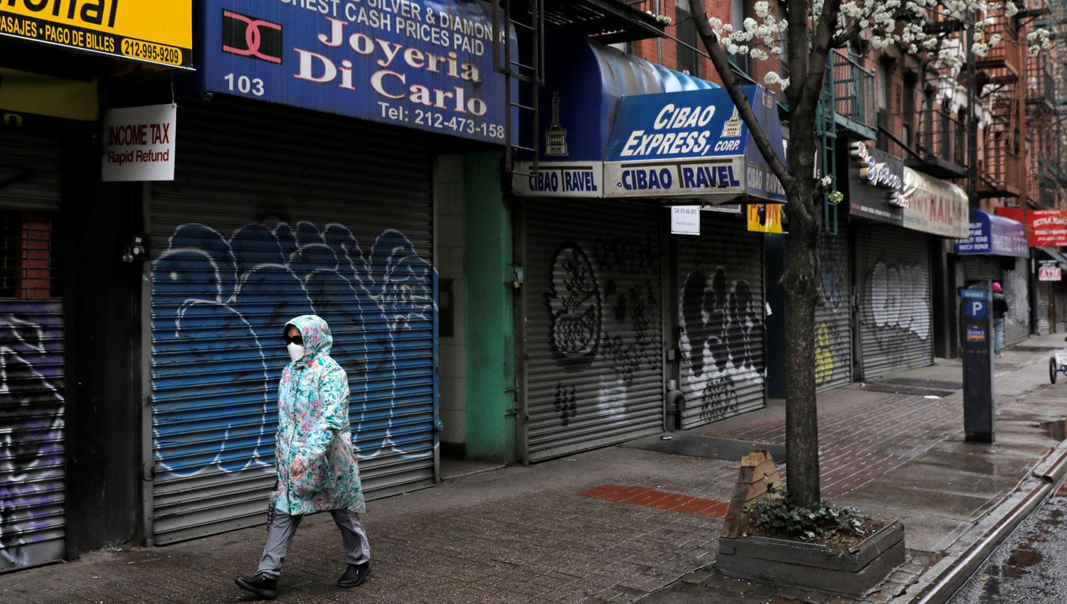 CERRADO. Una mujer camina por la zona sur de Manhattan, que en una jornada de persianas bajas.