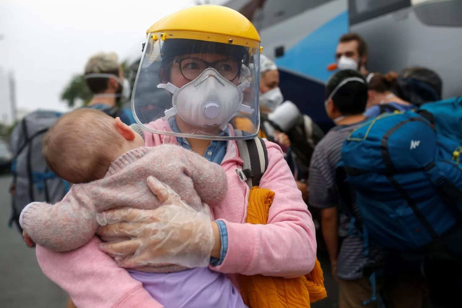 CORONAVIRUS. Una mujer con mascarilla carga a su bebé en las calles de Perú.