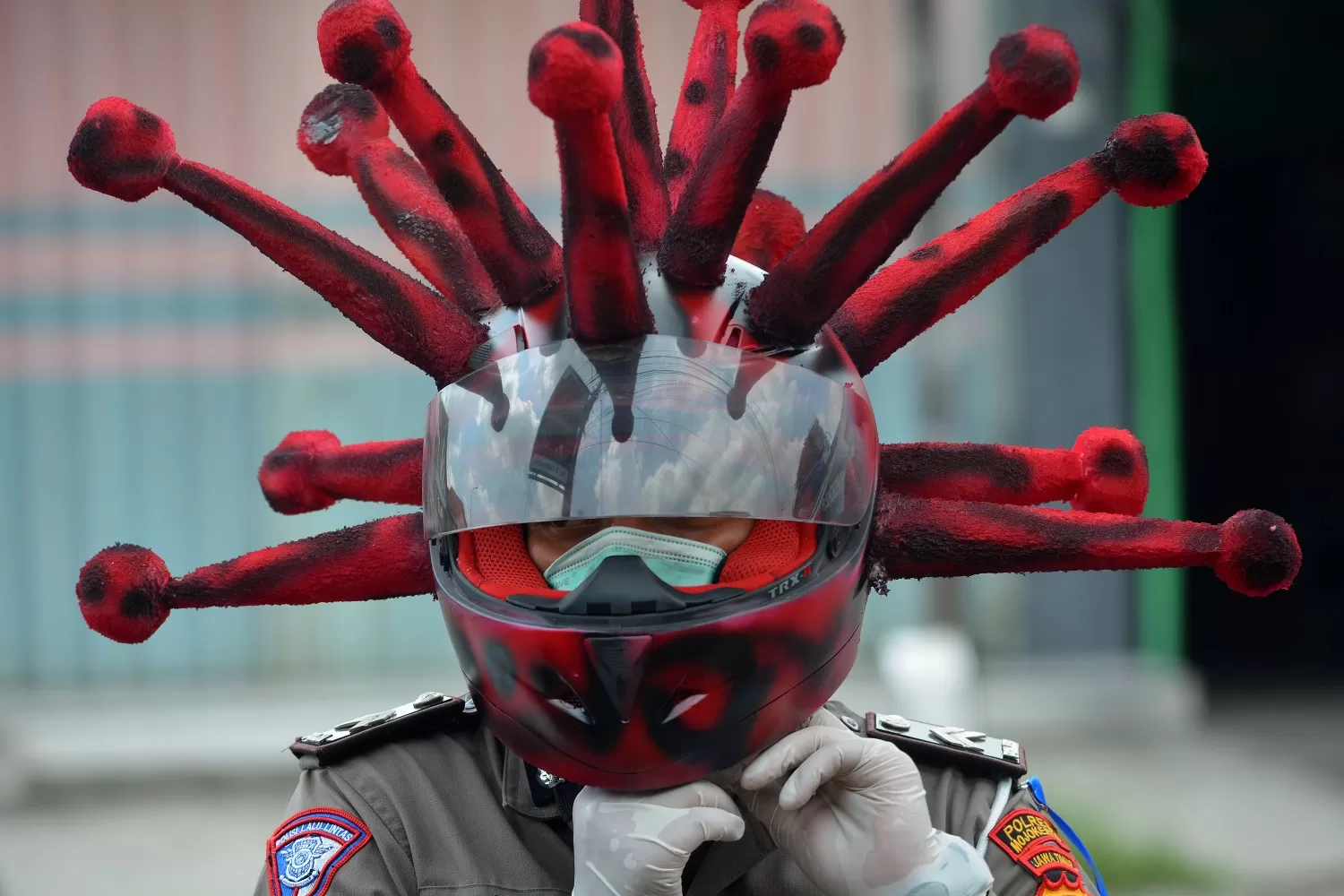 CORONAVIRUS. Un oficial de policía usa un casco que representa el coronavirus, para hacer campaña por el uso de máscaras faciales en Indonesia.