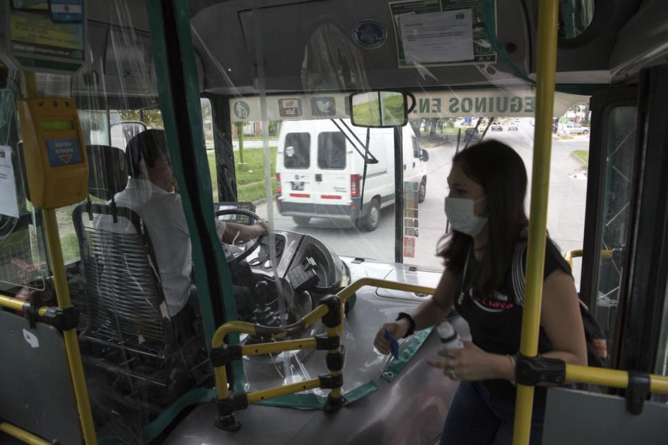 PROTEGIDO. Una mujer sube a un colectivo tucumano; el chofer la observa desde atrás del plástico que lo aísla de los pasajeros.