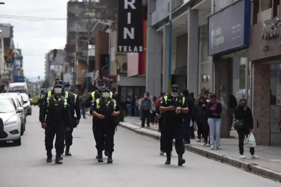 CONTROLES. Un grupo de policías patrulla el microcentro; de fondo, la gente hace cola para pagar cuentas.