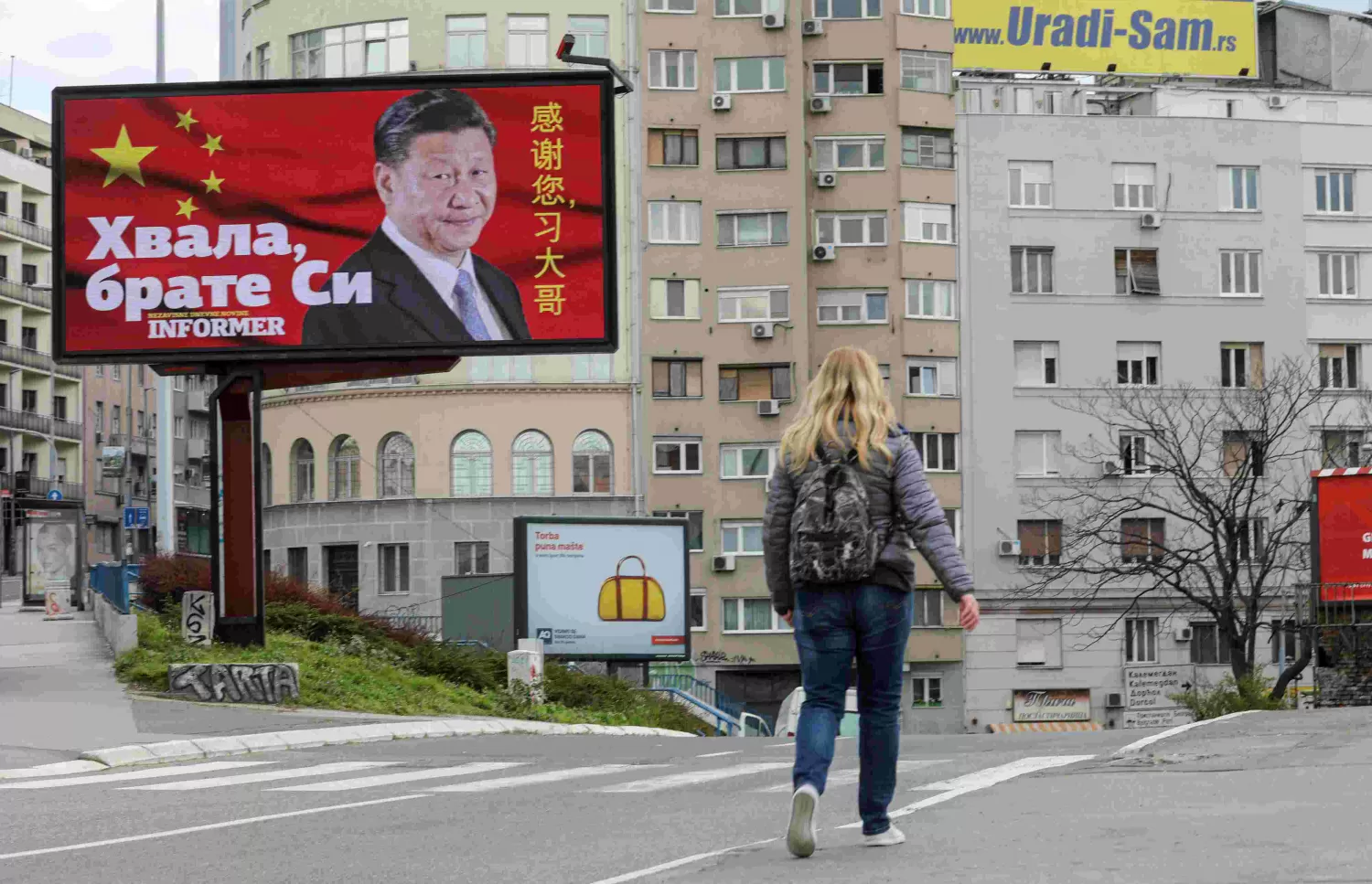 LA IRONÍA. Una mujer camina cerca de un enorme cartel de Belgrado, que dice Gracias hermano Ji, en referencia a la liberación de la pandemia. REUTERS