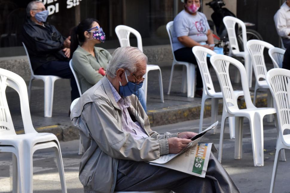 EN LA ESPERA. Un adulto mayor lee el diario antes de entrar al banco.