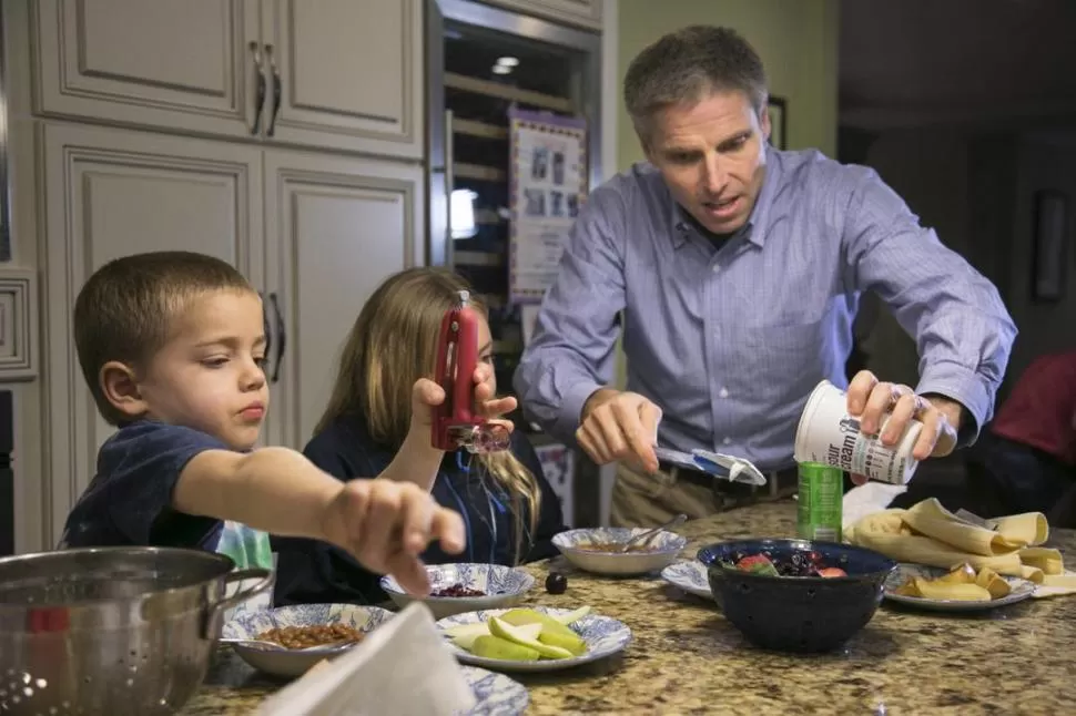 FAMILIA. Un padre les sirve la comida a sus hijos. La presencia de la familia es fundamental, según el estudio. reuters