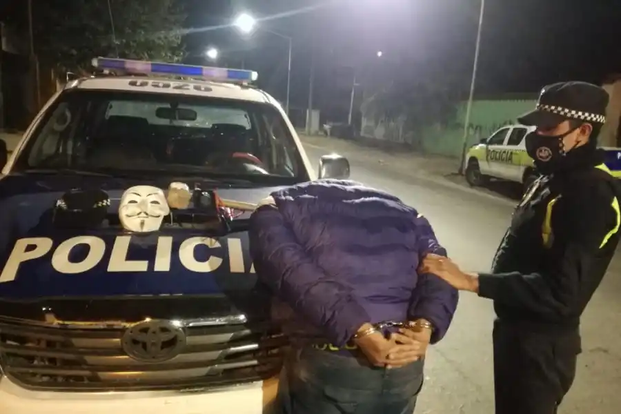 ATRAPADO. El joven aprehendido, contra el patrullero; junto a él, la máscara y los demás secuestros. FOTO: Ministerio de Seguridad.