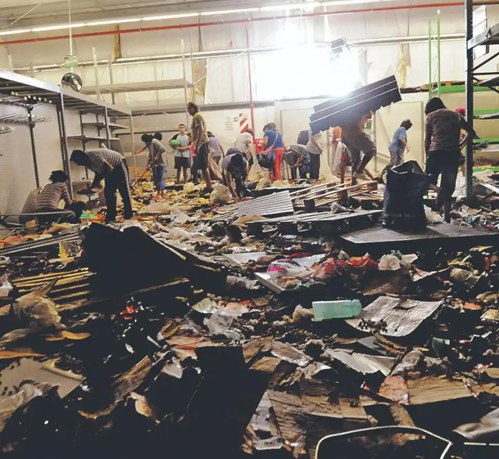 LAS SECUELAS DE LA BARBARIE. Trabajadores y curiosos observan y tratan de ordenar uno de los depósitos que fueron arrasados por los saqueadores. 