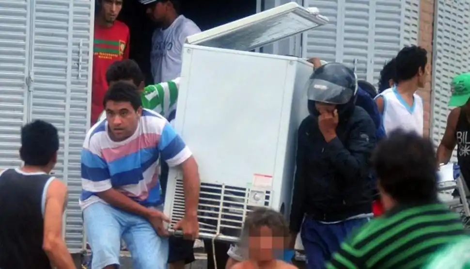 EL CAOS SE APODERABA DE LAS CALLES. Dos personas fueron retratadas mientras se apoderaban de una heladera de gran tamaño que robaron de un local comercial. 