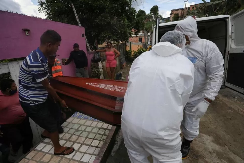 EMERGENCIA. Trabajadores de SOS Funeral llevan el cajón de una de las víctimas mortales del coronavirus en la ciudad de Manaos, Brasil. Reuters