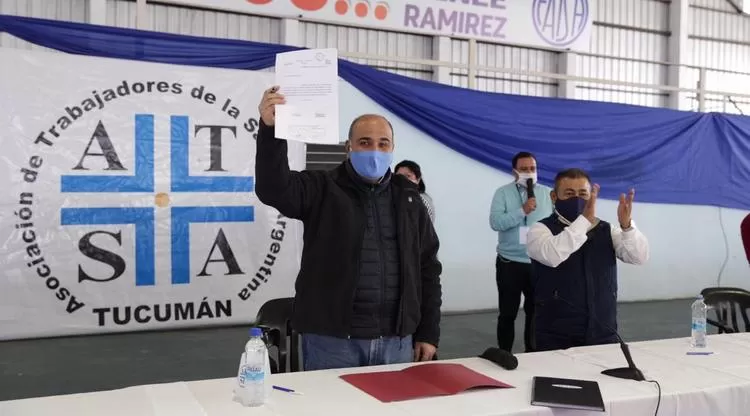 EN ATSA. Manzur muestra la ley promulgada, mientras Ramírez aplaude. Foto: Comunicación Pública
