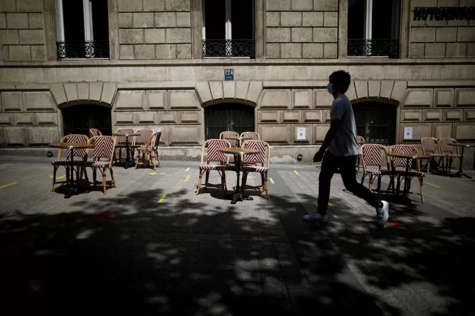 PARIS. Un hombre con barbijo junto a mesas que respetan la distancia. Reuters (archivo)