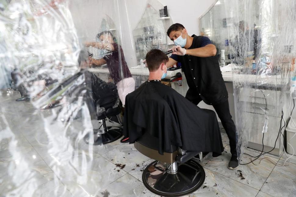 BARBEROS. Con barbijo y cortinas plásticas para separar a los clientes, abrieron las peluquerías  en Washington.  