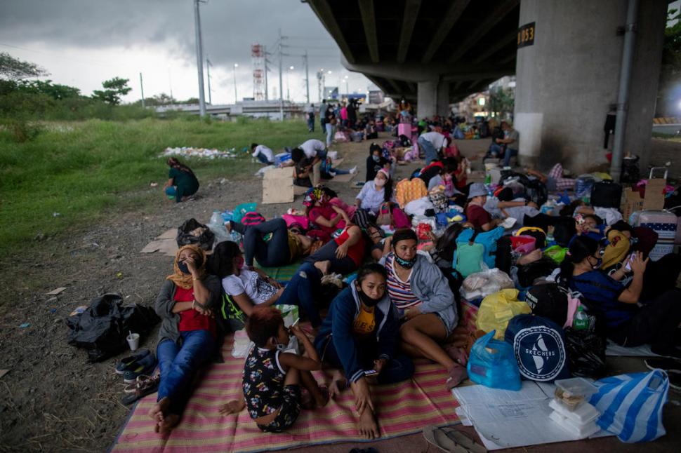 VARADOS. Trabajadores filipinos esperan en el aeropuerto de Manila, un transporte para salir de la ciudad.  