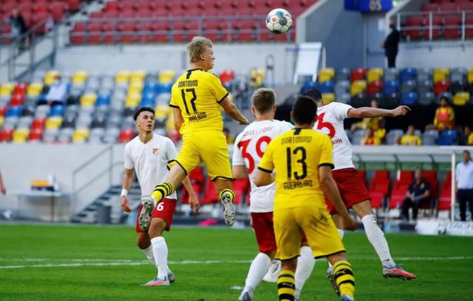 GRAN FIGURA. El noruego Haaland se eleva para cabecear, en lo que se convirtió en un agónico gol para Dortmund. 