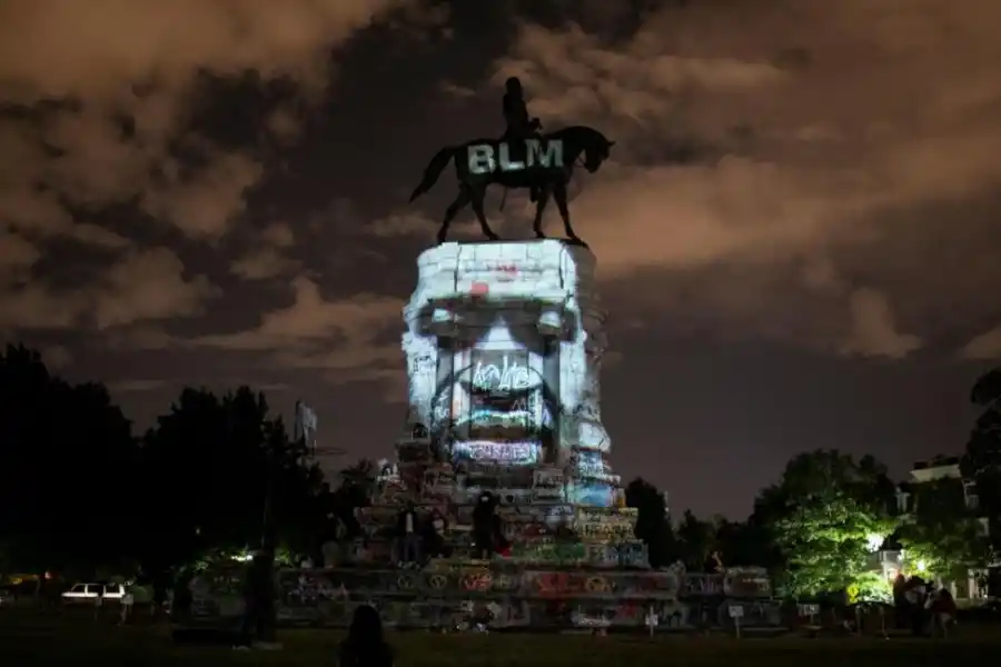 CONTRASTE. El artista Dustin Klein proyectó la imagen de George Floyd sobre la estatua del general confederado Robert E. Lee, en Virginia. fotos Reuters