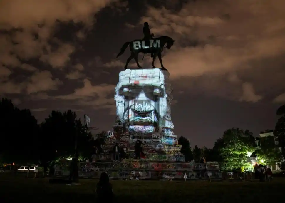 CONTRASTE. El artista Dustin Klein proyectó la imagen de George Floyd sobre la estatua del general confederado Robert E. Lee, en Virginia. fotos Reuters