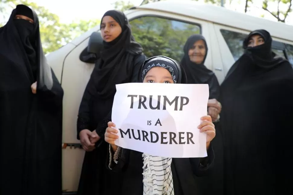 RECLAMO. Una niña muestra un cartel que dice “Trump es un asesino”, durante un homenaje a Soleimani.  Reuters