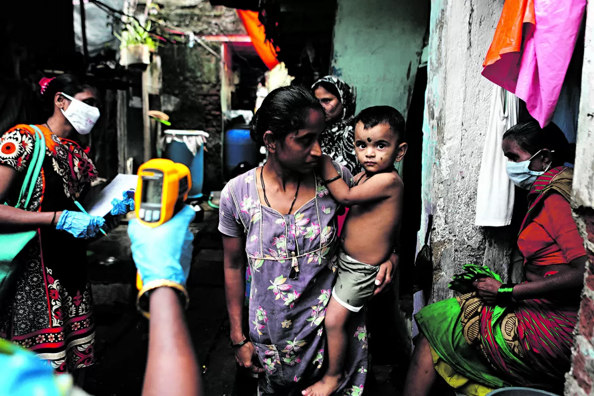 CAMPAÑA. Trabajadores de la salud toman la temperatura a los transeúntes en una calle de Bombay, en India. 