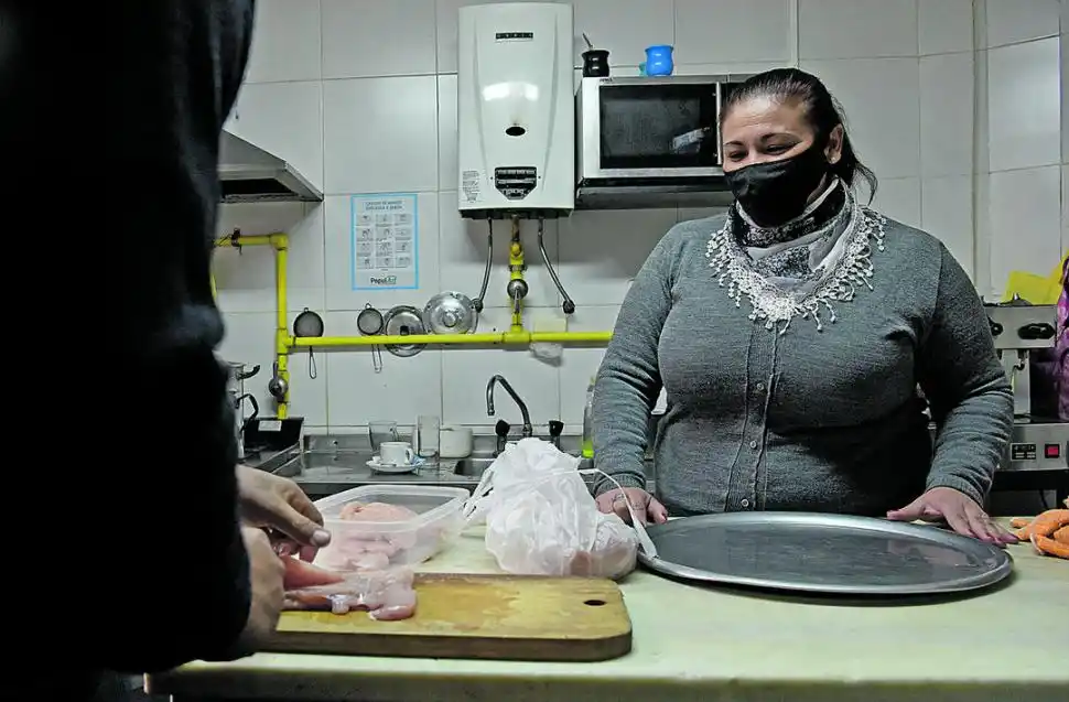 ACTIVIDAD EN LA COCINA. Una bandejera sonríe detrás del barbijo.  