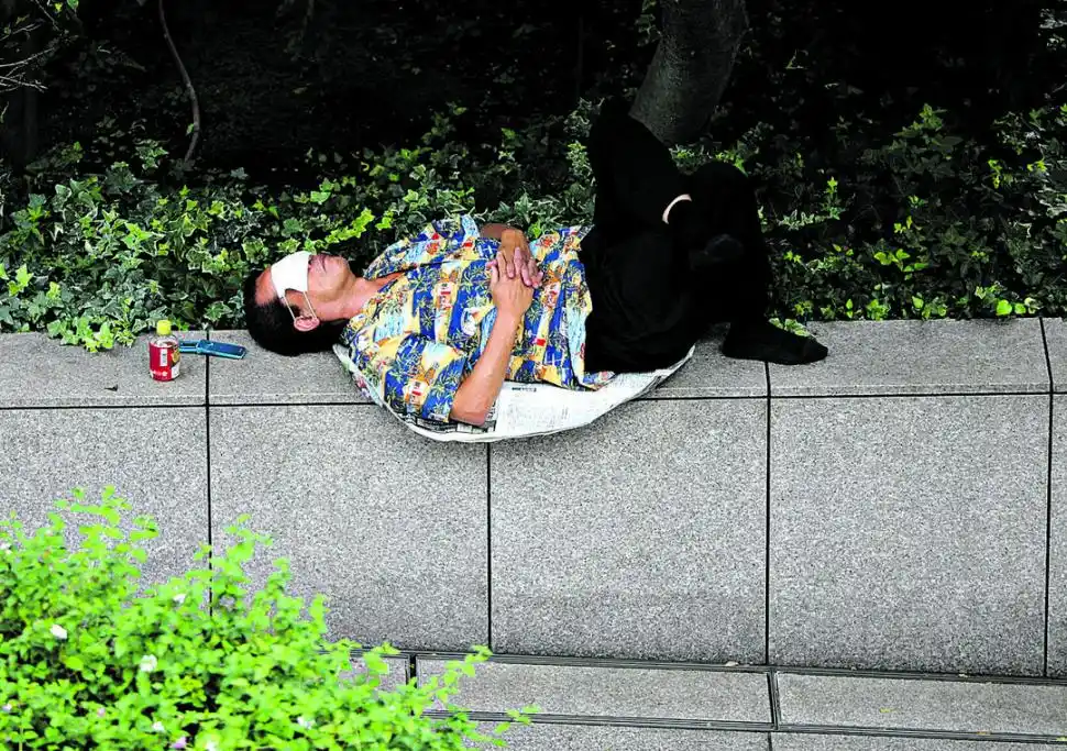 la siesta.- Con el barbijo como antifaz, un hombre se toma un descanso en una calle de Tokio.  fotos Reuters