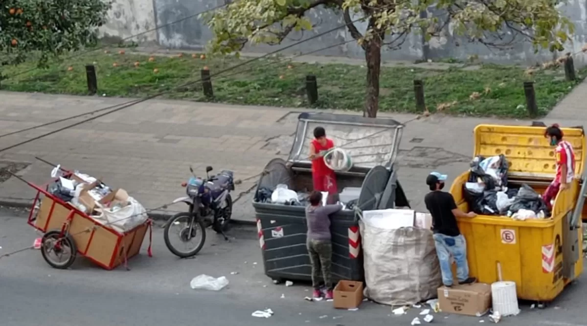 Adultos y niños que revisan en la basura frente al edificio de Tribunales
