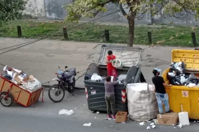 Adultos y niños que revisan en la basura frente al edificio de Tribunales