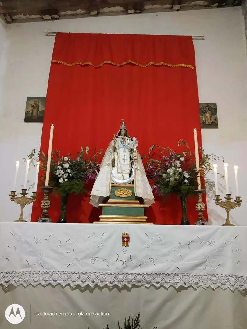 ALTAR CASERO. La imagen de la Virgen está decorada con flores y velas a su alrededor, además de un mantel blanco. 