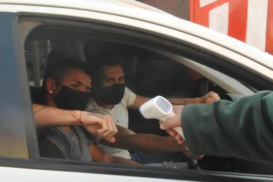 PROTOCOLO. Carrizo se toma la temperatura antes de ingresar al estadio; Gonzalo Rodríguez sonríe tras el barbijo.  