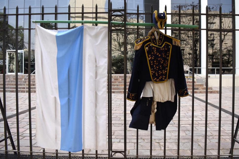 EMBLEMAS COLGADOS. La bandera tucumana y una réplica teatral del traje de Belgrano, del grupo Los Intérpretes, fueron puestas en la reja que rodea la Legislatura de Tucumán.
