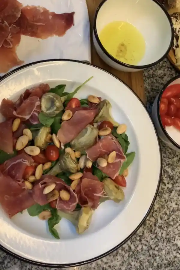 ENSALADA. Alcauciles braseados, rúcula, jamón crudo y almendras.