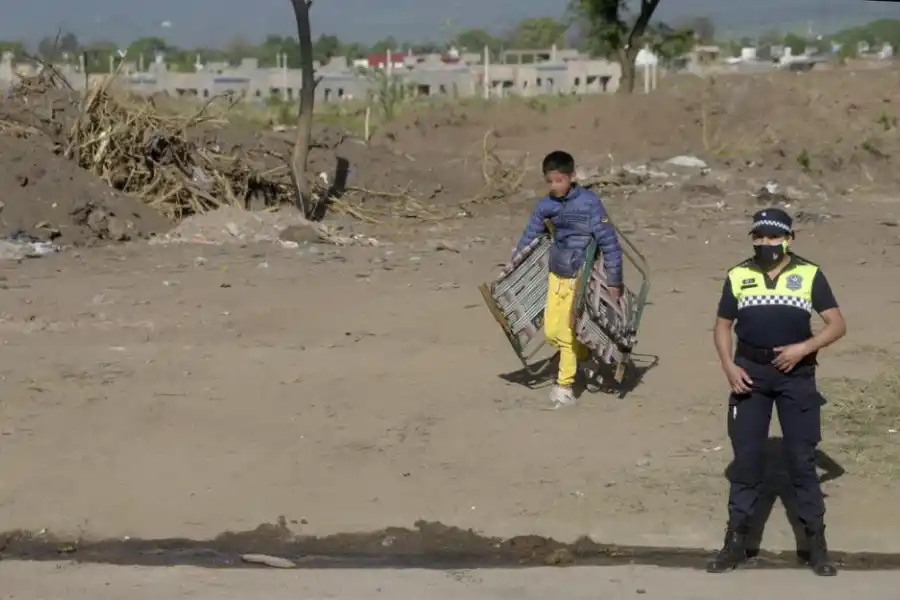 LA OTRA CARA. Un niño carga dos reposeras durante el desalojo efectuado.