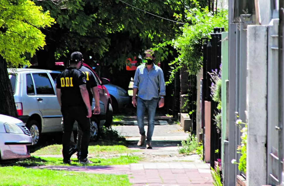 OPERATIVO. El neurocirujano Luciano Luque camina por la vereda de su casa durante el allanamiento, a la par de agentes de la Policía bonaerense. Se quejó de la actitud de los agentes. 