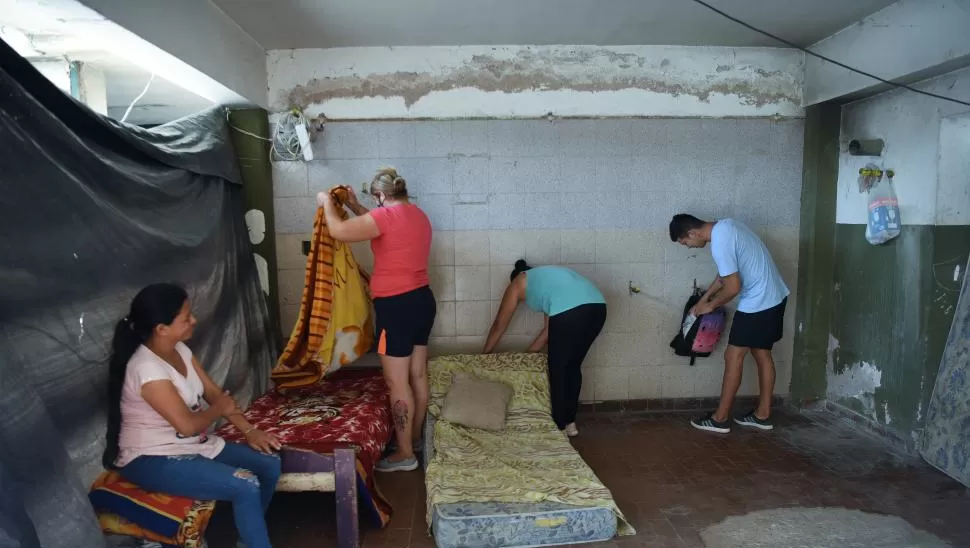 CUARTO IMPROVISADO. A la mañana reacomodan las escasas pertenencias y después se juntan en grupos para matear. En el predio reina la escasez.